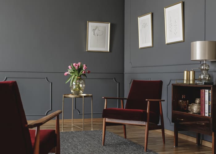 Elegant psychologist's office interior with two red armchairs facing each other between a golden table with flowers and vintage, wooden cabinet. Real photo