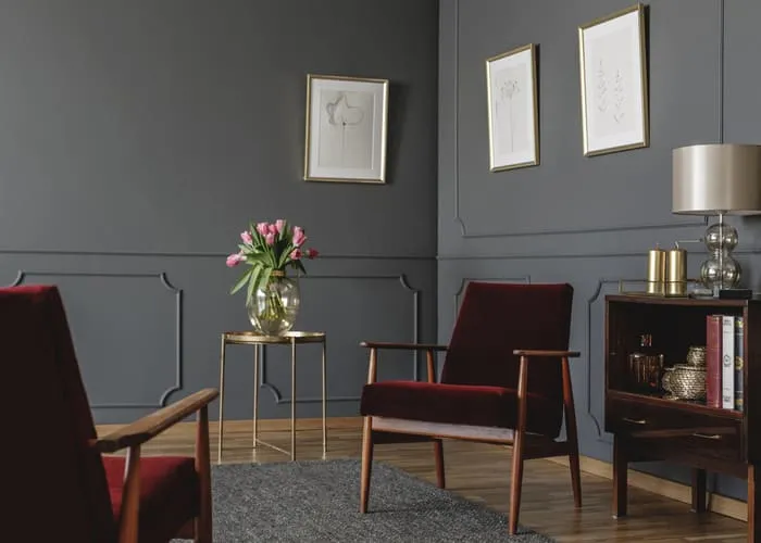 Elegant psychologist's office interior with two red armchairs facing each other between a golden table with flowers and vintage, wooden cabinet. Real photo