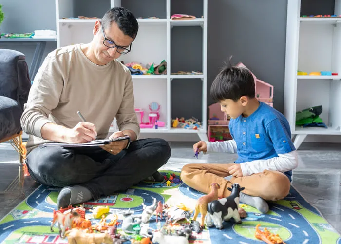 A Professional Child Psychologist Observing Little Boy Playing With Toys At The Psychotherapy Session